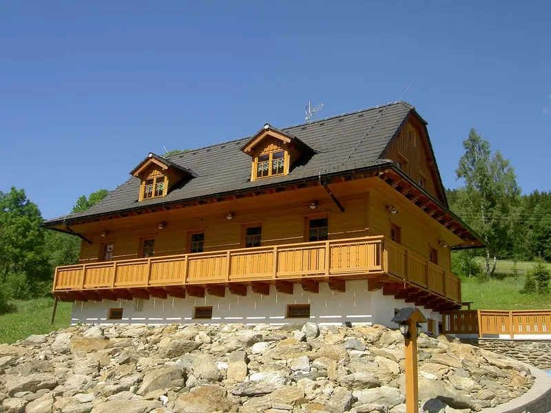 Dřevěná horská Chata 7 Dvorů s dlouhým balkonem a kamennou zídkou pod lesem